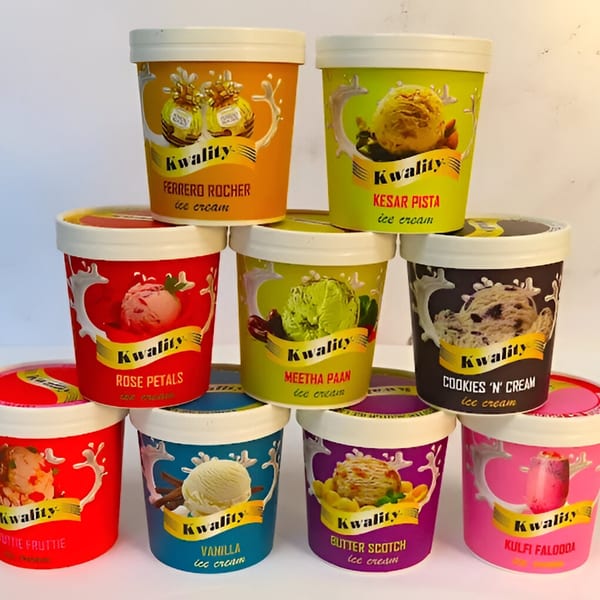 A colorful display of Kwality ice cream tubs in various flavors, including Ferrero Rocher and Kesar Pista.