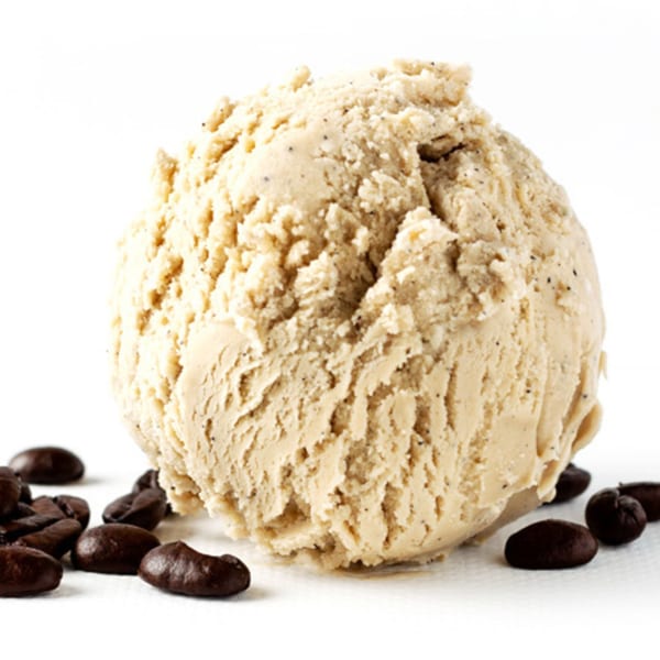A scoop of coffee ice cream with coffee beans scattered around it on a white surface.