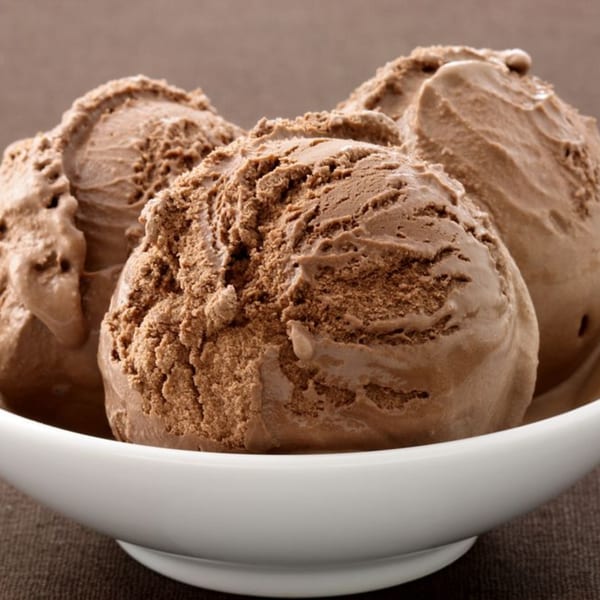 Three scoops of rich chocolate ice cream in a white bowl from Kwality Norwood.